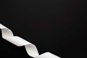 close up curled white ribbon black background corner 1 Fita branca - violência contra as mulheres.